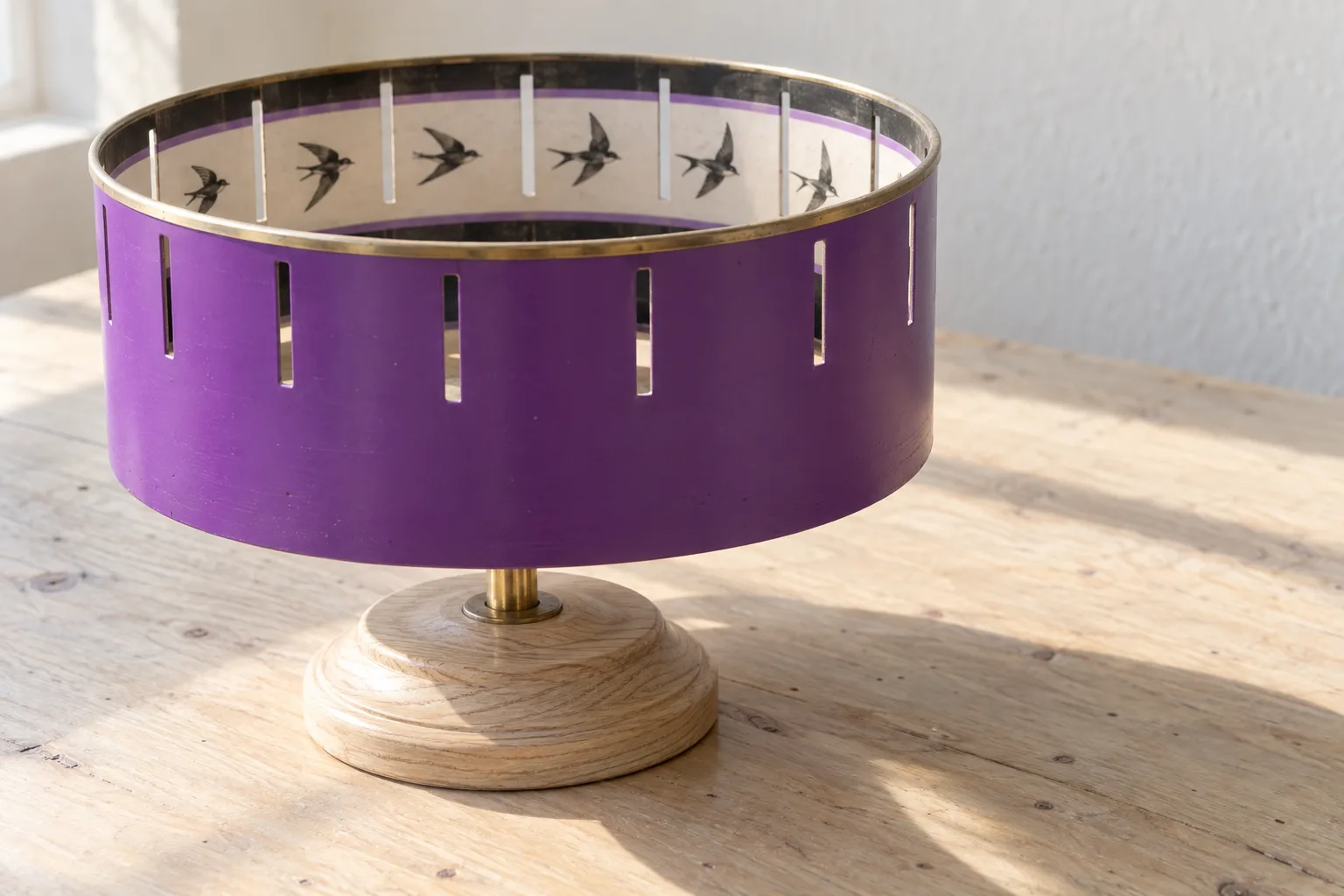 An orchid-lacquered zoetrope on a pale timber table in the foyer's morning sun, a painted swift visible through its slits