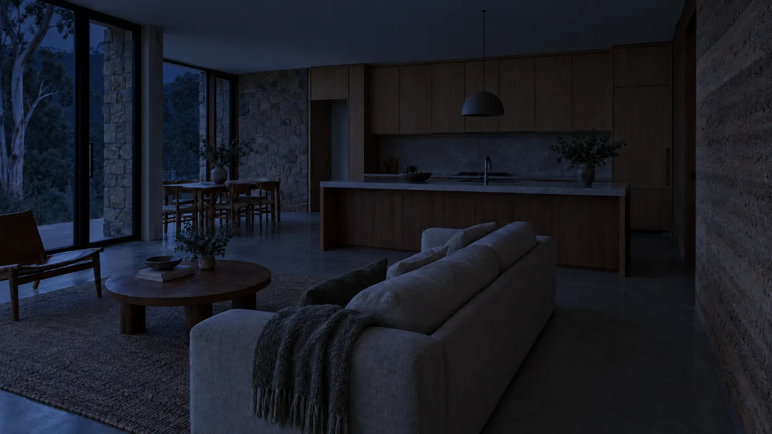 A living room and kitchen at night with every light off, the sofa, island and joinery just visible in blue light from the garden door