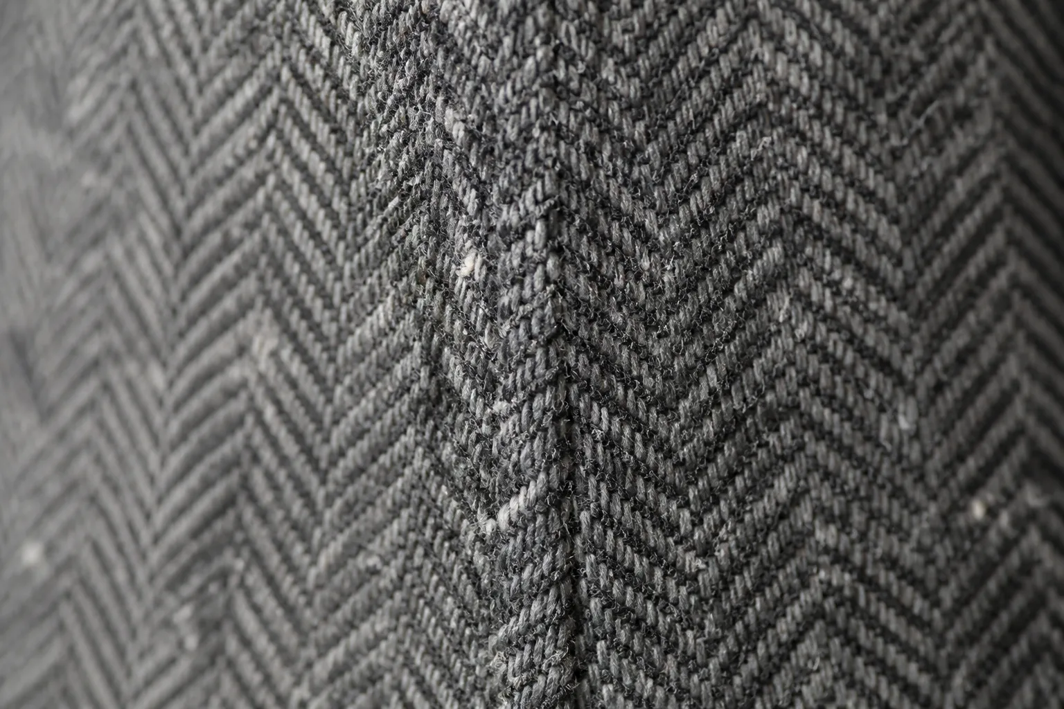 Slate herringbone seen very close: columns of chevrons, one broken where the twill turns back.