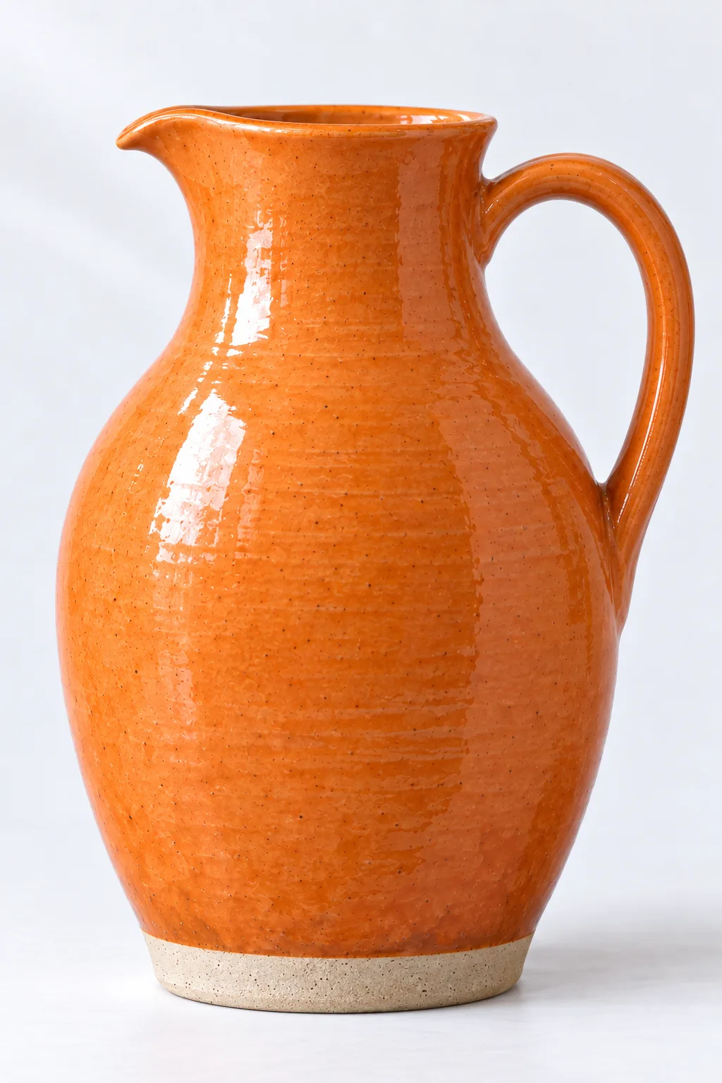 A tall tangerine-glazed jug in profile, its spout to the left and its handle to the right.