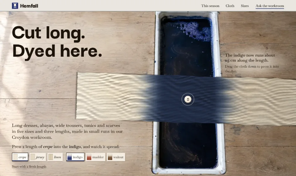 The front page from above: cream crepe laid across an indigo dye trough in an oak table, the headline on the timber