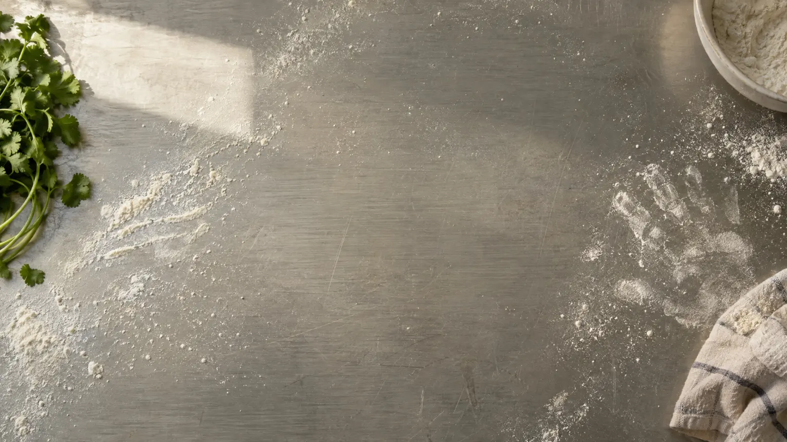 A floured steel bench under a kitchen window, clear in the middle