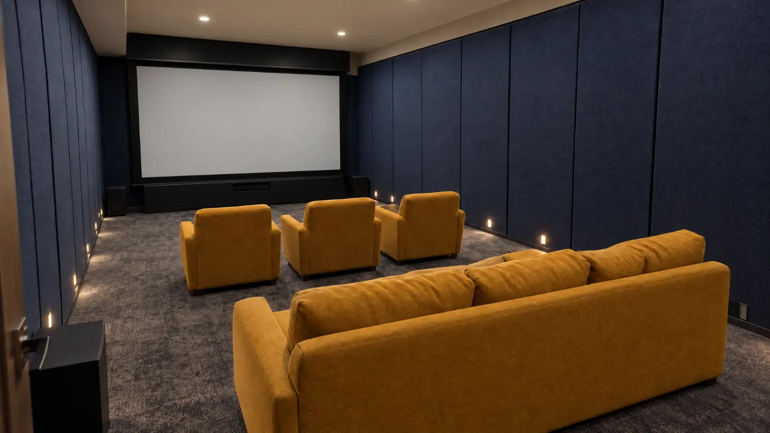 The same cinema room with the lights up: the screen off and pale grey, navy fabric walls, three mustard armchairs and the mustard sofa in soft even light