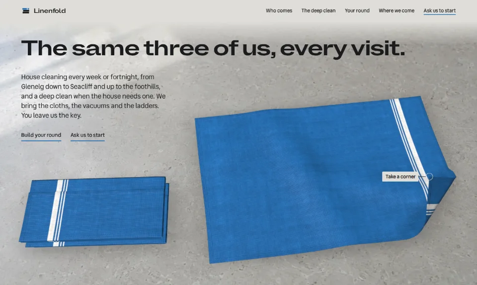 The front page: a French-blue tea towel lying open on a pale stone bench under a long, wide headline, one corner turned back