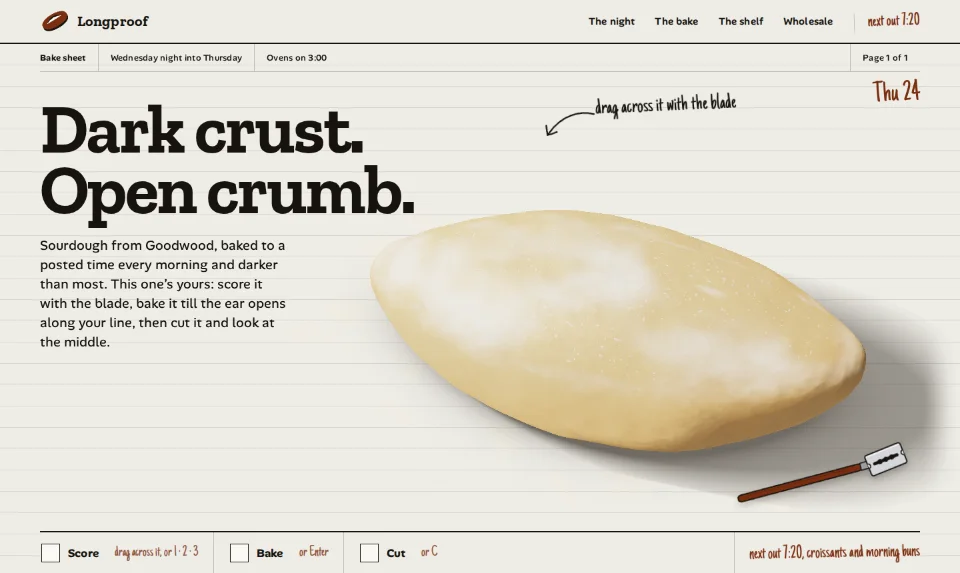 The front page: a floured, unscored sourdough batard on a ruled chalk-white sheet under a heavy slab heading, a strip of Score, Bake and Cut boxes below