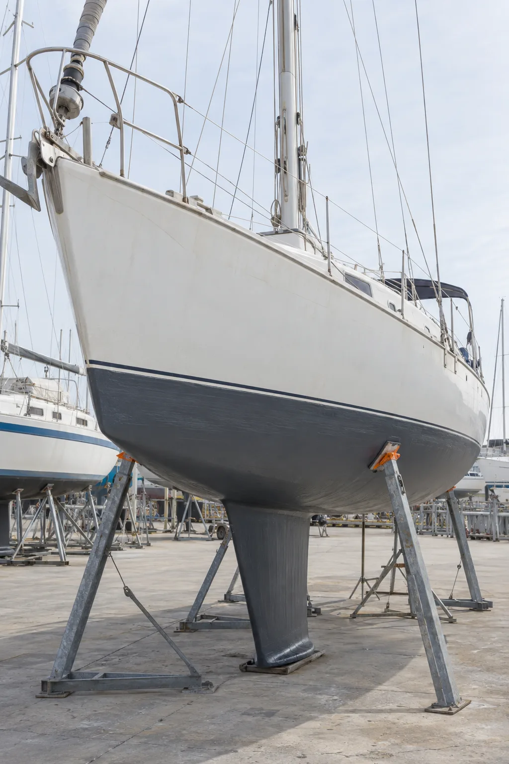 Looking up at the Bay 15 sloop’s bow and dark fin keel, propped on steel stands on the hardstand.