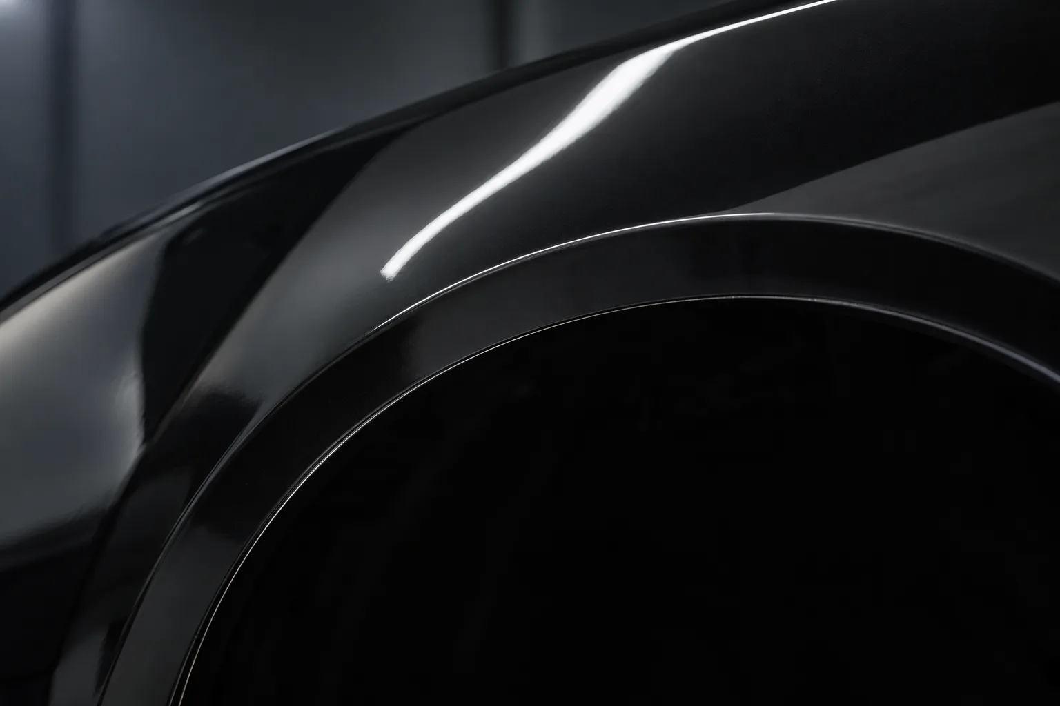 The curve of a black front guard over the wheel arch, clear film on the paint, its edge a faint line just inside the arch.