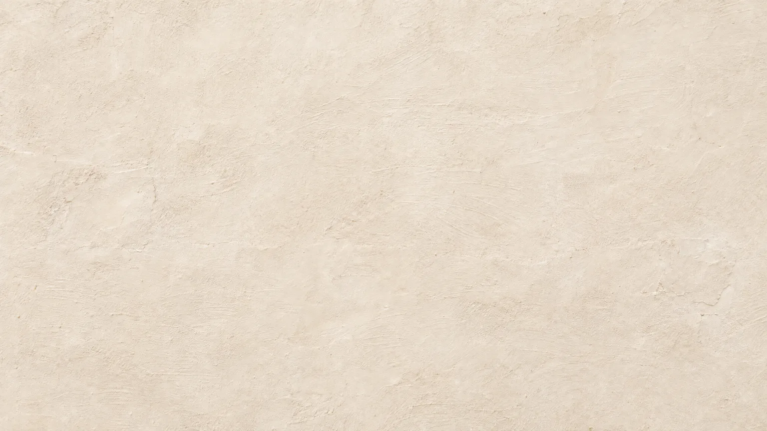 An old rendered wall in a pale chalky limewash, cloudy and matt, lit by low morning sun